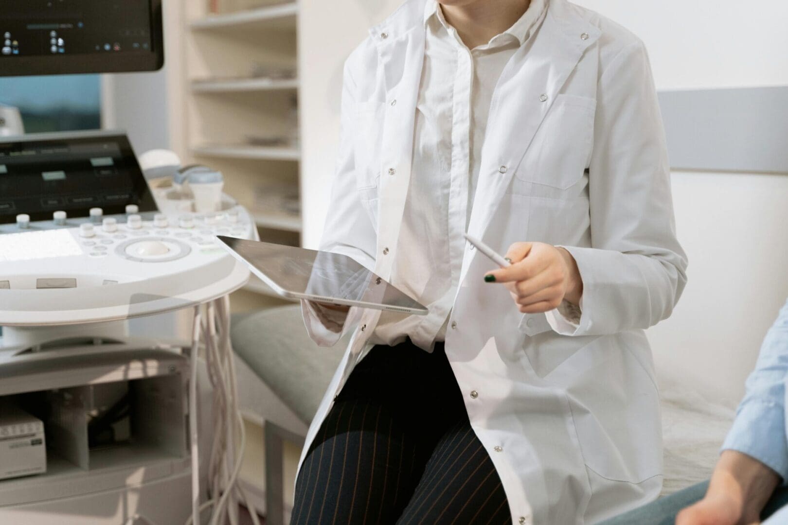 A Healthcare professional in a white coat using a tablet for digital patient records in a clinic.