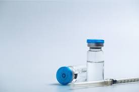 The image shows two vials and an injection placed on the table.