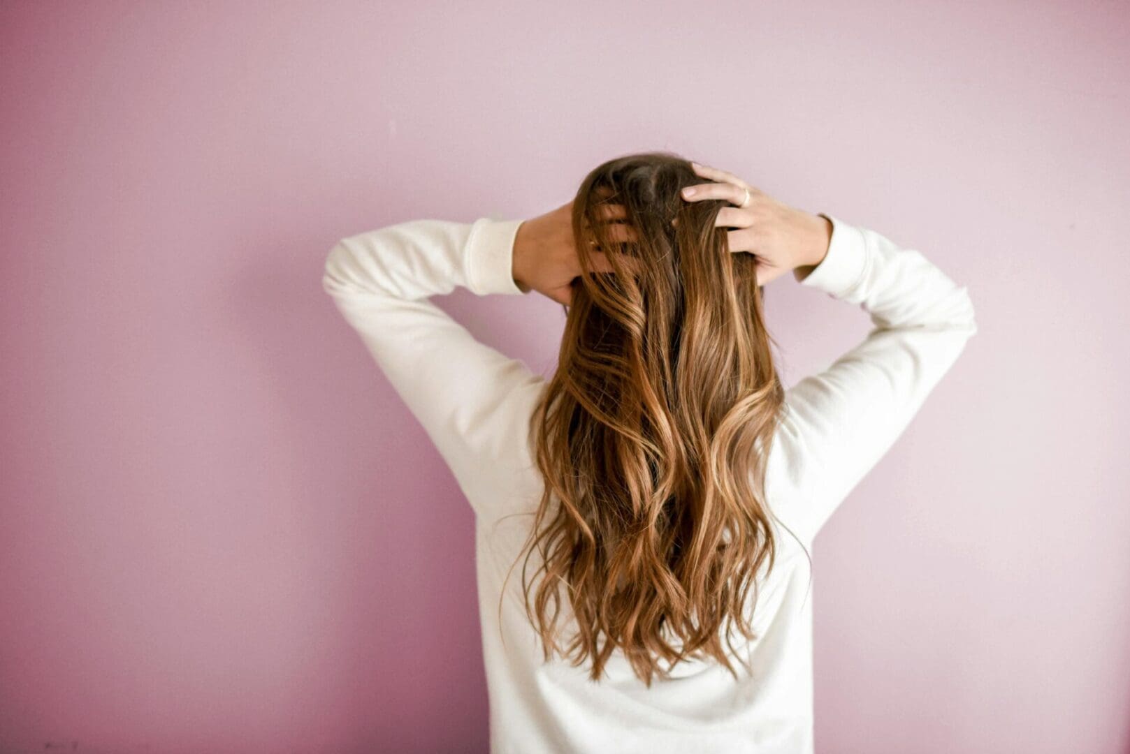 The image shows a woman with long, voluminous hair demonstrating hair restoration results.