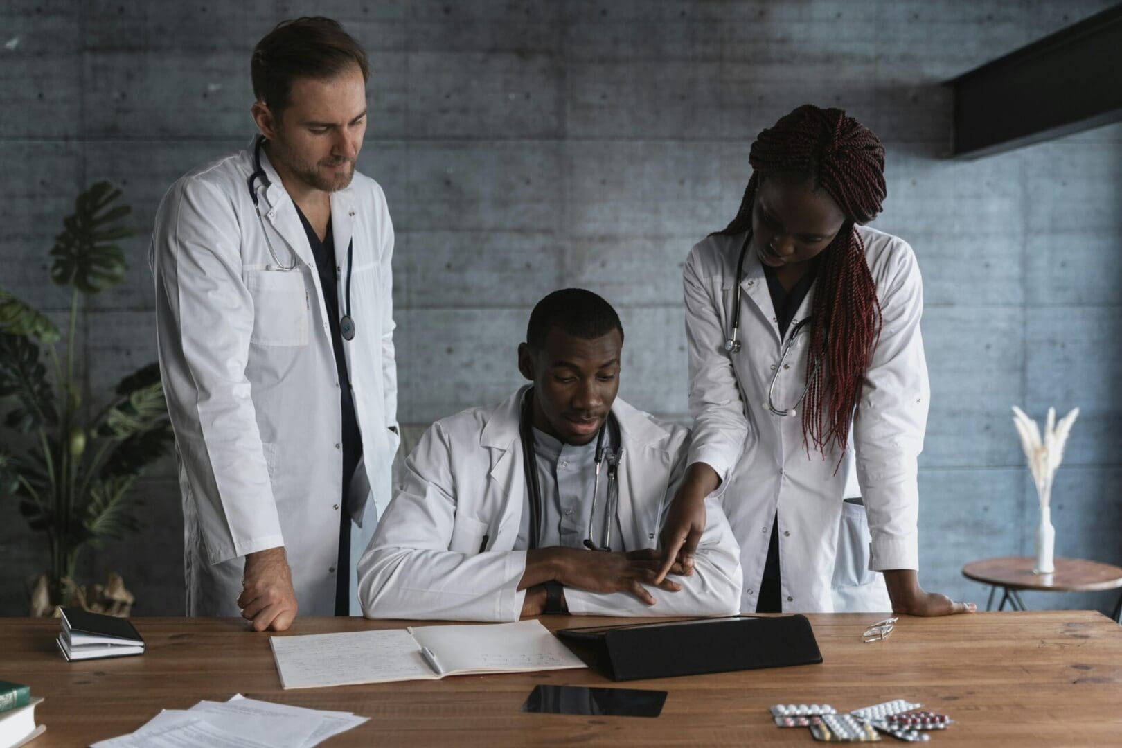 A group of three healthcare providers consulting over patient reports in a clinic.
