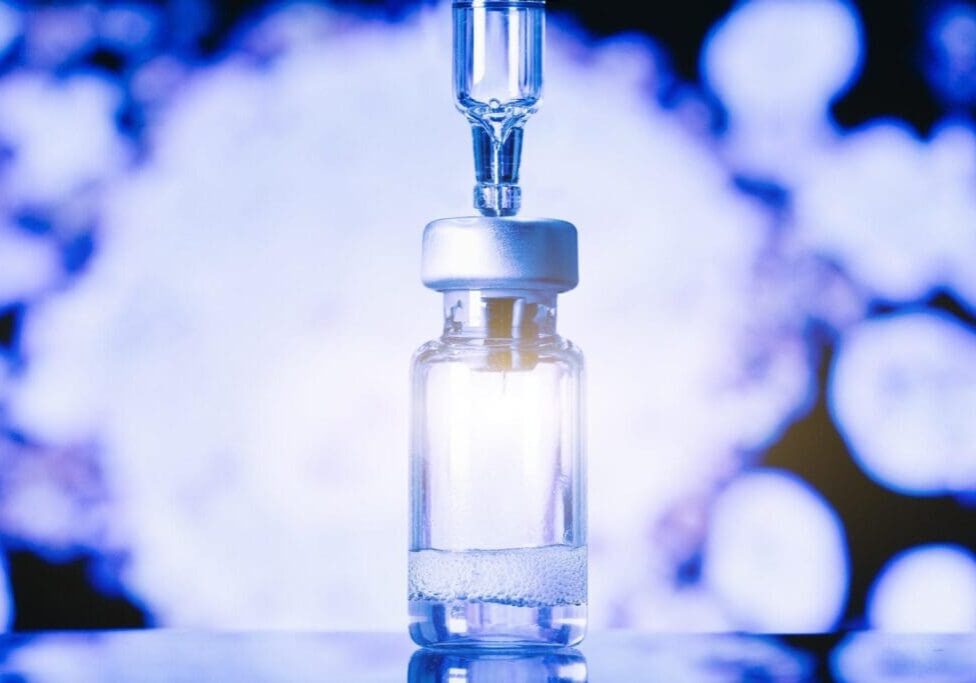 A lab technician wearing protective gloves and goggles carefully handles a test tube