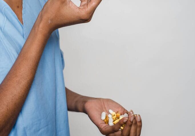 The image shows a patient holding supplement capsules in her hand.