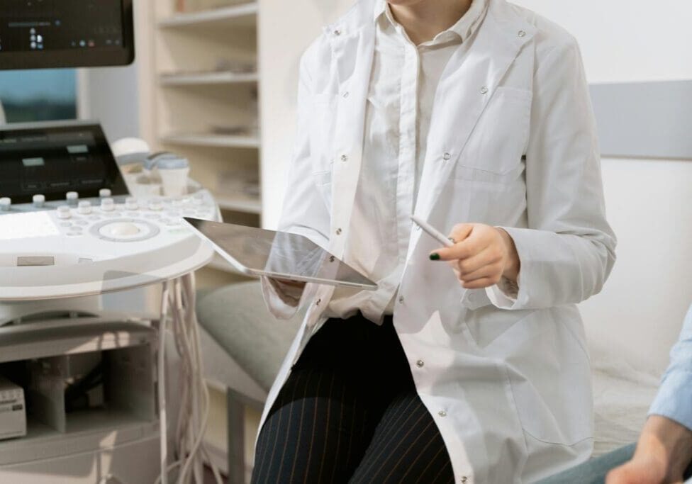 A Healthcare professional in a white coat using a tablet for digital patient records in a clinic.