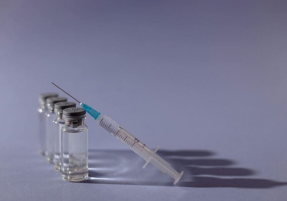 The image shows an injection and vials placed on a table.