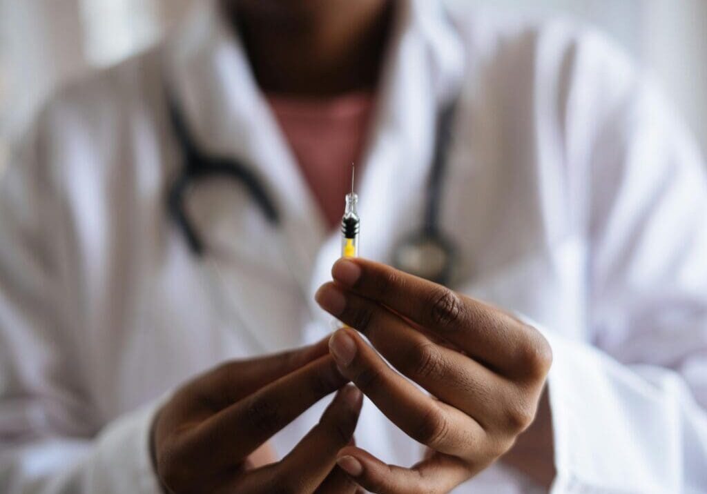 A Healthcare professional in a white coat holding a syringe as part of a medically supervised treatment plan.