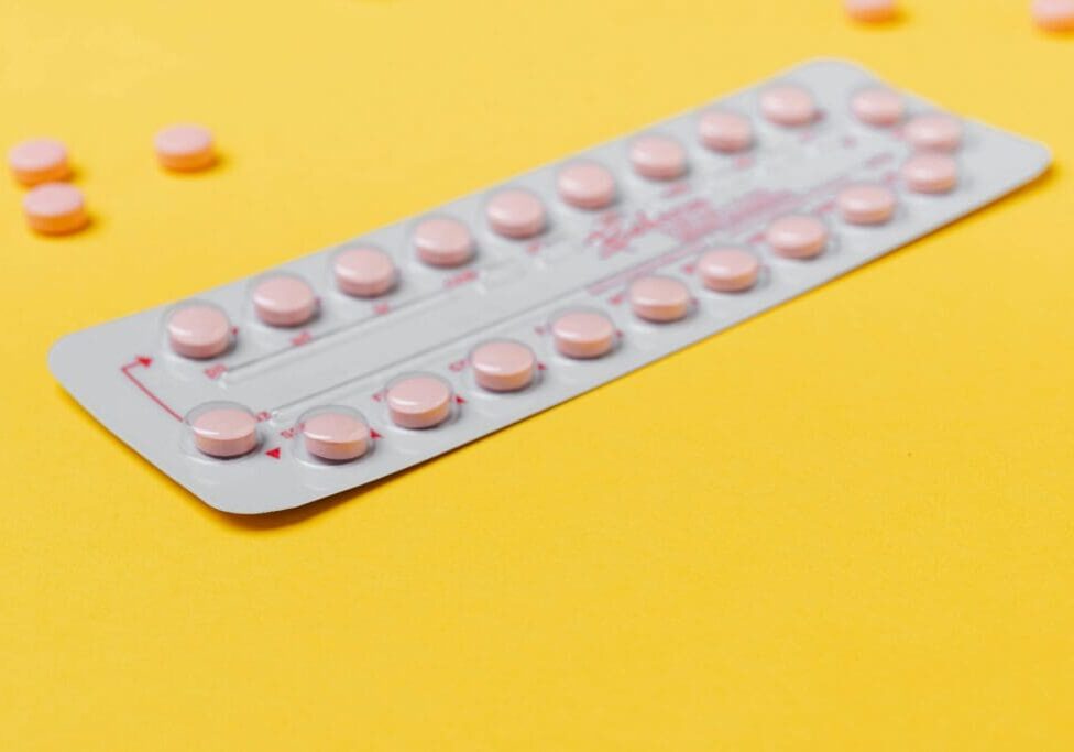 The image shows a blister strip surrounded by few pills in a yellow background.