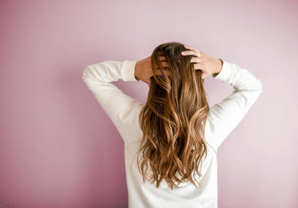 The image shows a woman with long, voluminous hair demonstrating hair restoration results.