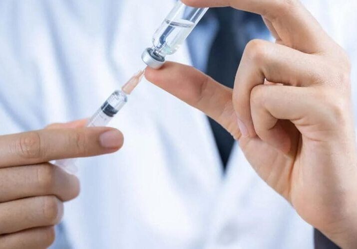 The image shows a healthcare professional administering injection.